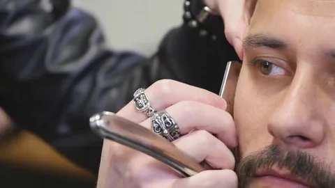 Barber with old-fashioned black razor shaving bearded man Stock Footage 69075674