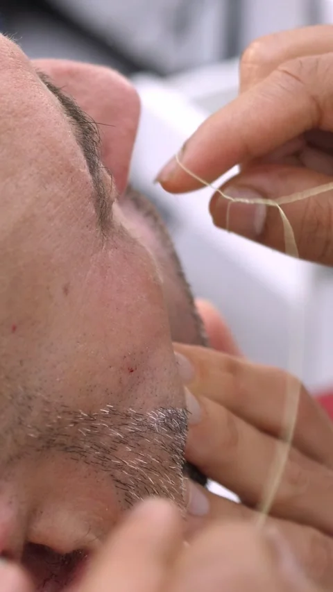 Barber performing eyebrow threading on client (close view) Stock Footage 318581190