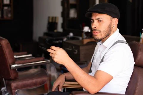 Barber playing with the scissors in his hands sitting in his barbershop chair. Stock Photos