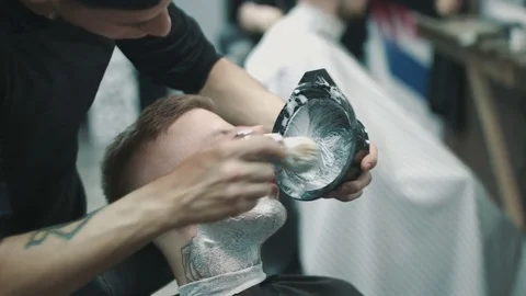 Barber putting some shaving cream on a client. 動画素材 80024574