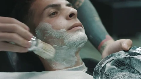 Barber putting some shaving cream on a client. Video stock 80027657