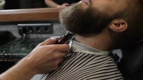 Barber shave the beard of the client with electric razor Stock Footage