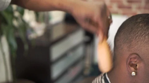 Barber shaves black man's head using electric razor and brush in professional Stock Footage