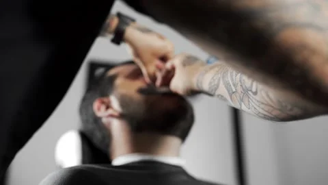 Barber shaves customer with straight razor blade, man's haircut and shaving at Stock Footage 91977139
