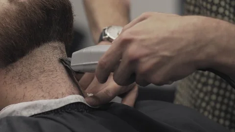 Barber shaving beard with electric razor in male salon. Barber trimming beard Stock Footage 104771679