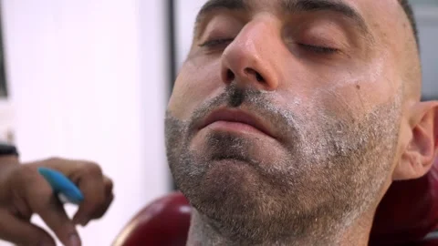 Barber shaving beard with razor on young man classic grooming Stock Footage 333195778