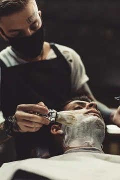 Barber shaving client Stock Photos
