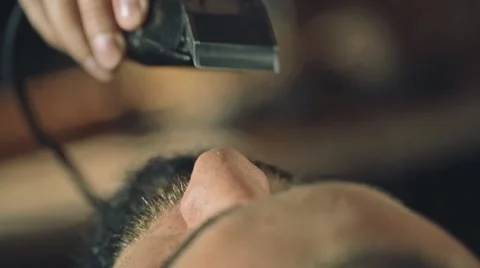Barber shaving a client's beard with electrical shaving machine, close up Stock Footage 67315770