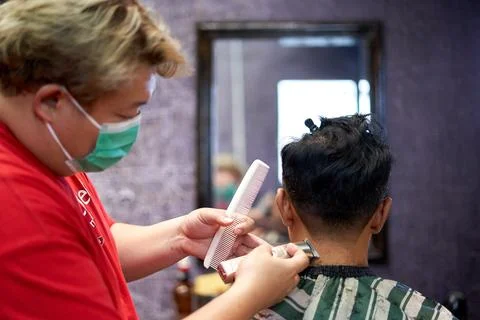 Barber shaving the nape of a client using a clipper and comb Stock Photos