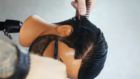 Barber shows scratching techniques and cutting hair on a mannequin Stock Footage 143951122