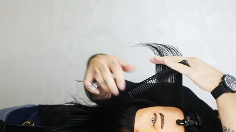 Barber shows scratching techniques and cutting hair on a mannequin Stock Footage 143951500