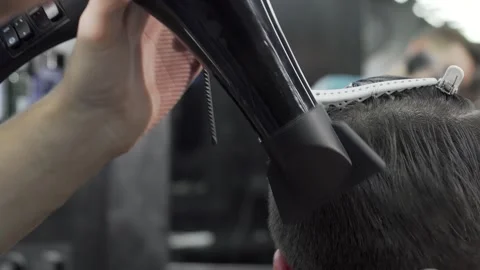 Barber skillfully blow drying a client's hair for a stylish finish Stock Footage 311952543