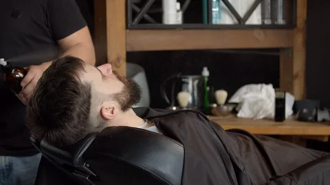 Barber spraying water on head of client Stock Footage 127183672