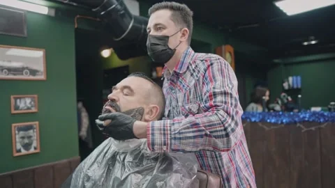 The barber spreads the paint on the client's beard Stock Footage 144668023
