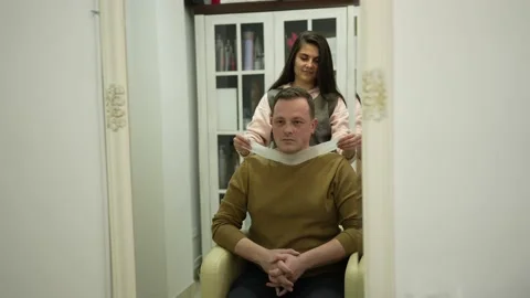 Barber starts his work with customer and puts a protective paper strip on neck. Stock Footage 236474057