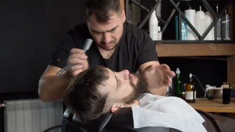 Barber trimming beard of client Video stock 127175058