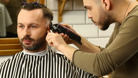Barber trimms hair of client with machine Stock Footage 91214726