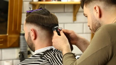 Barber trimms hair of client with machine Stock Footage 91216138