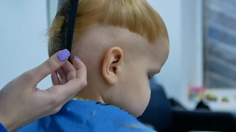 Barber trying to make haircut while little boy turn head 库存影片 103087101