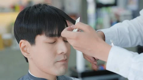 The barber uses scissors and a comb to trim the hair in front of the client.  스톡 동영상 153953503