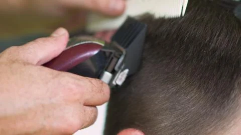 Barber using clippers to cut a young man's hair Stock-Fotos