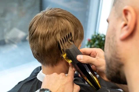 Barber using comb and shaver to cut hair. Professional hairdresser shaving Stock Photos