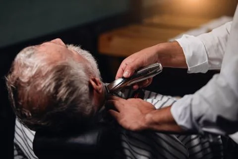 Barber using electro shaver while working at beauty salon Stock Photos