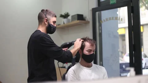 Barber using hair dryer at the barber shop wearing protective mask during cor Stock Footage 139930605