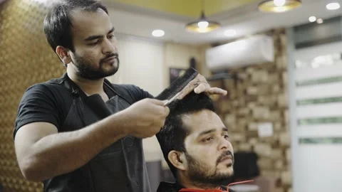 A barber is using scissor while giving a haircut to the client inside the salon Stock Footage 151843104