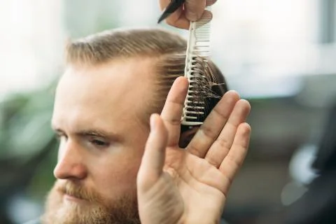 Barber using scissors and comb in barbershop Stock Photos