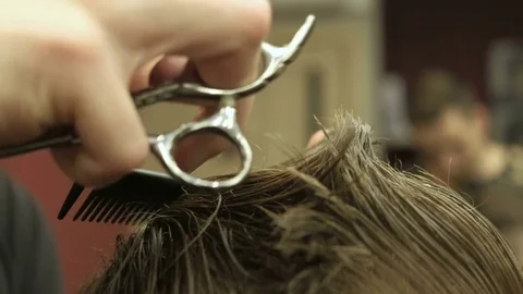 Barber using a scissors to cut a mans hair. Close up Stock Footage 76967299