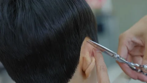 The barber is using scissors to trim hair around the ears.Professional hairdr Stock Footage 153791942