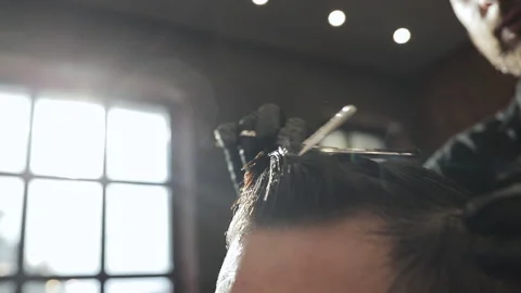 Barber wearing black gloves doing a haircut for client with scissors at barber Stock Footage 194521208