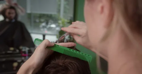 Barber wets clients hair using spray bottle and combs before cutting. Attractive Stock Footage 313085546
