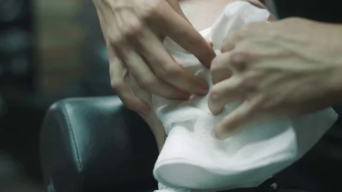 Barber wipes off with a napkin the face of the client. Stock Footage 80025349