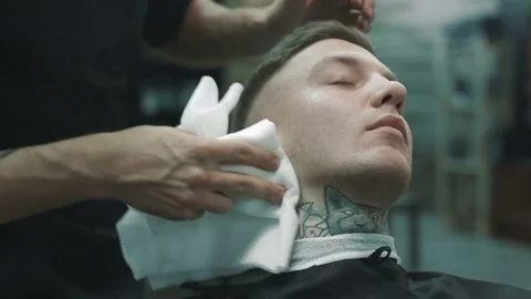 Barber wipes off with a napkin the face of the client. Stock Footage 80025408