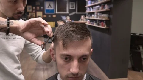 Barber works with scissors for thinning over the back of the head and client's Stock Footage 81513157