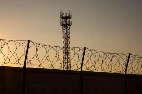 Barbwire prison wall with barbed wire fence coiled razor wire perimeter fence Stock Photos