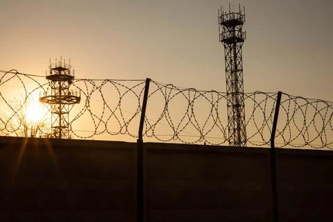 Barbwire prison wall with barbed wire fence coiled razor wire perimeter fence Stock Photos