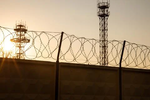 Barbwire prison wall with barbed wire fence coiled razor wire perimeter fence Stock Photos
