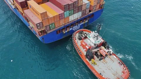 Barcelona Express cargo ship is assisted into port by harbour tug boat Stock Footage 345524384