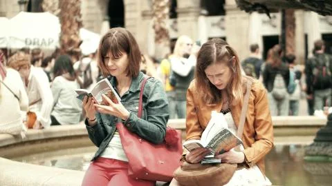 BARCELONA, SPAIN - APRIL, 16, 2017. Two young women reading city tourist guide Stock Photos
