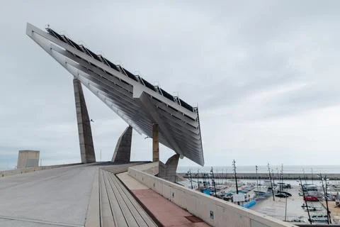 Barcelona's iconic solar panel structure overlooks a marina on a cloudy day Stock Photos