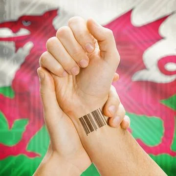 Barcode ID number on wrist and national flag on background - Wales Barcode... Stock Photos