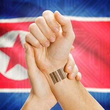Barcode ID number on wrist and national flag on background - North Korea B... Stock Photos