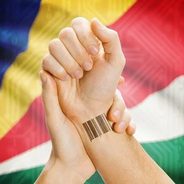Barcode ID number on wrist and national flag on background - Seychelles Ba... Stock Photos