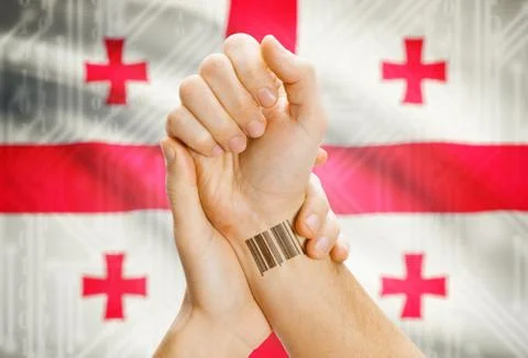 Barcode ID number on wrist of a human and national flag on background - Georg 스톡 사진