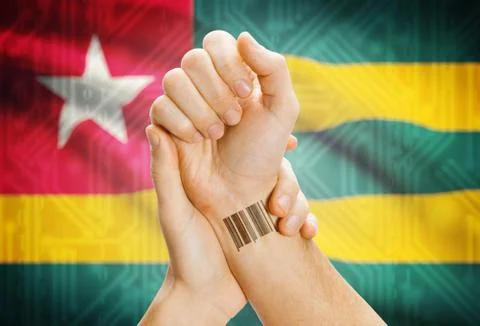 Barcode ID number on wrist of a human and national flag on background - Togo Stock Photos