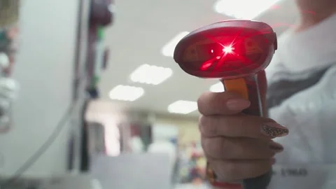 Barcode scanner flashes red beam close-up. Female salesperson scans a quick Stock Footage 165450258