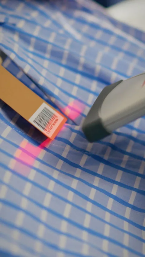 Barcode scanning on a blue checkered fabric with a handheld scanner in a ret Stock Footage 331535780